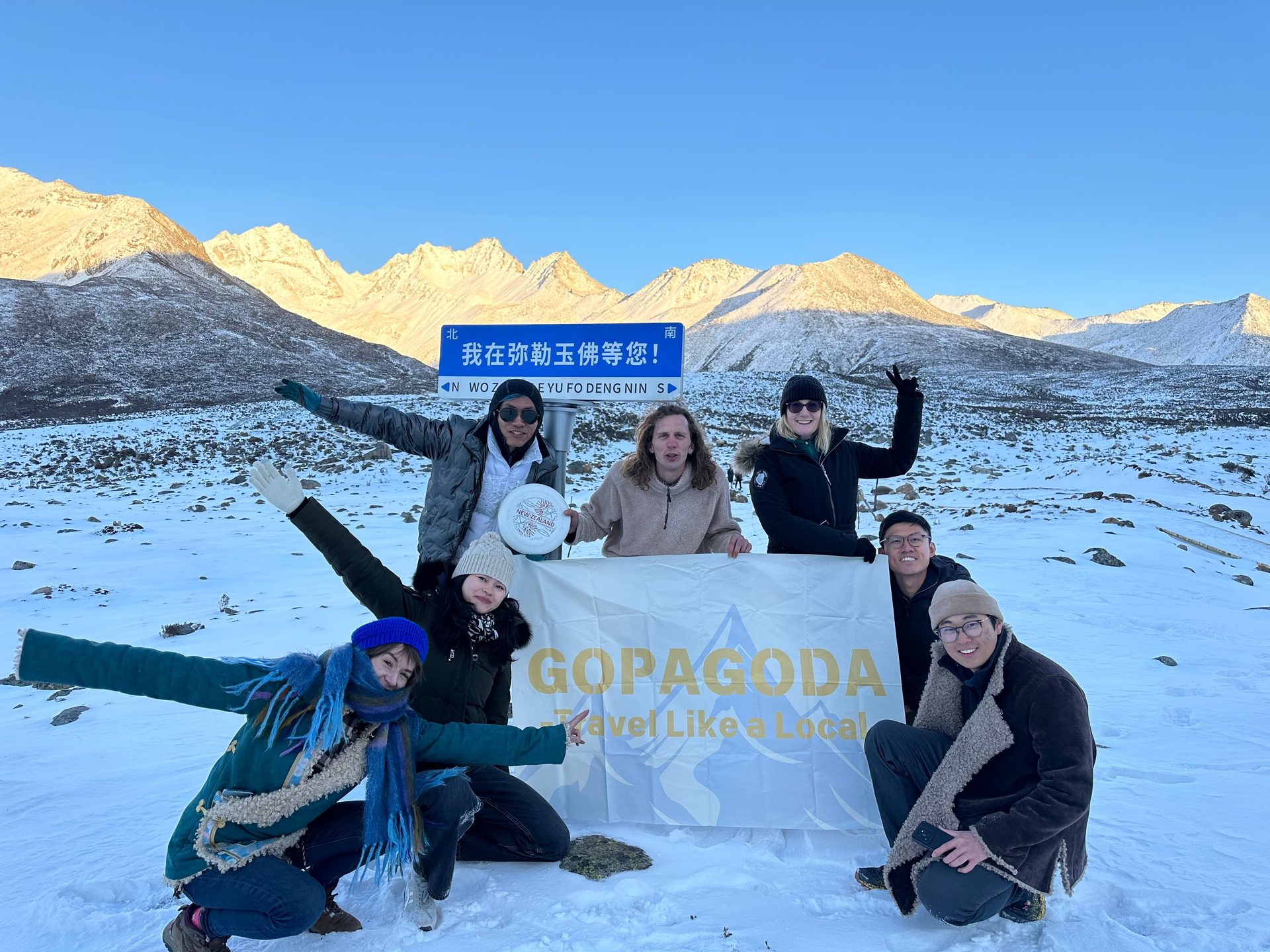 Happy travelers at snowy mountains with Gopagoda flag